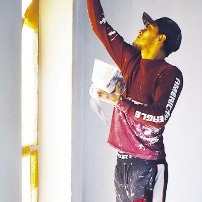 Emmanuel Coyoy textures the perimeter of a window with plaster in preparation for paint crews in the new Pre-K building at Nance Elementary. CDN | Caleb Blanchard Prepping for paint