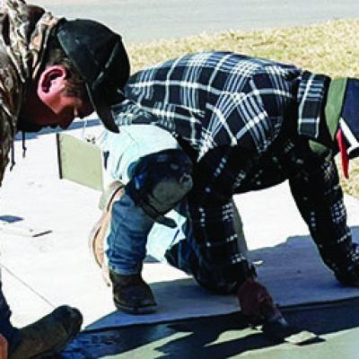 Aurelio Ortiz, left, and Carlos Lopez pave the sidewalk in front of the new building at Southwest Elementary School. CDN | Michael Maresh