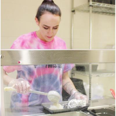 Kayla Walker prepares a tray for one of the after-school meals at Clinton Middle School. CDN | Emily Stephens After school feed program offered