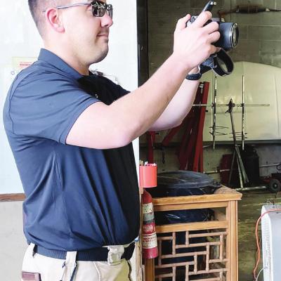 Clinton Police Detective Michael Bouziden assisted in the arrest of local business owner William Folsom at Folsom’s Auto Body & Paint Friday afternoon. Bouziden was tasked with photographing the inside of the shop. CDN | Kelcie Hartley-Wolfe Body shop owner arrested for alleged embezzlement