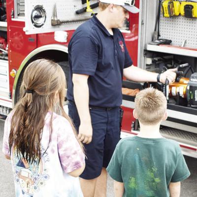 Firefighter Collin Wieder shows Summer Playground kids Paeton Eaton, left, and Tiernan Stevens the Jaws of Life at Southwest Elementary. CDN | Caleb Blanchard Tools of the trade