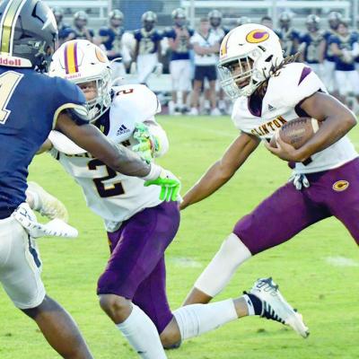 Javion Hill carries the ball and makes a cut while DeAndre Fanshier blocks Heritage Hall’s Jordyn Harris. CDN | John Kinsey Reds open district play at John Marshall