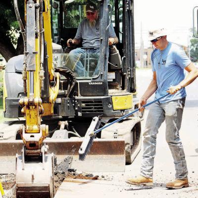 Donald Webb, left, operates an excavator to dig a trench as his son, Dalton Webb, maintains a clean work area by pushing dirt aside during water pipe replacement Thursday at S. 10th Street. CDN | Elisha Rangel Father-son duo at work
