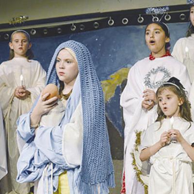 London House in the role of Mother Mary, center, holds Baby Jesus in her arms while performing at the Southwest Playhouse in “The Best Christmas Pageant Ever.” Other cast members holding candles from back row left, are Bailey Matthews, Makinley Motley Taking on the role