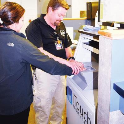 Custer County Jail Detention Officer Brian Conway, at right, assists Ana Ramos in the fingerprinting process for a Self-Defense Act ID. CDN | Litzy Silos Sheriff talks about jail operations