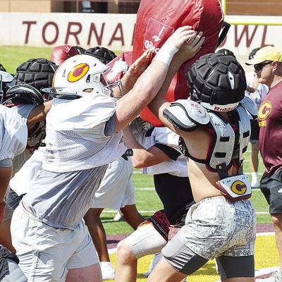 Clinton’s Brayden Fuller, left, pushes through the blocking pad held up by teammate Dyson Moss during practice in the Tornado Bowl. CDN | Sam Goodwyn
