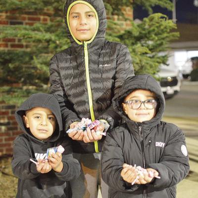 From left, Adriel Martinez, Sebastian Salas, and Eduardo Martinez show off their candy haul during the Clinton Festival of Lights Christmas Parade. CDN | Micah Ashcraft