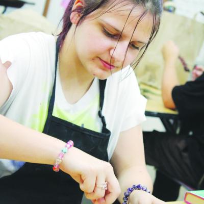 Malina Horhman, a high school student, smashes elderberries for an art project about making and using colors. CDN | Elisha Rangel Making art