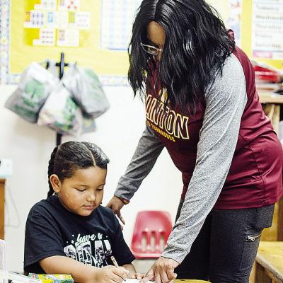 Khalil Douglas, left, gets help from Tosha Jones on a coloring book of Martin Luther King Jr. to celebrate Black History Month at Eastside Academy. CDN | Sam Goodwyn