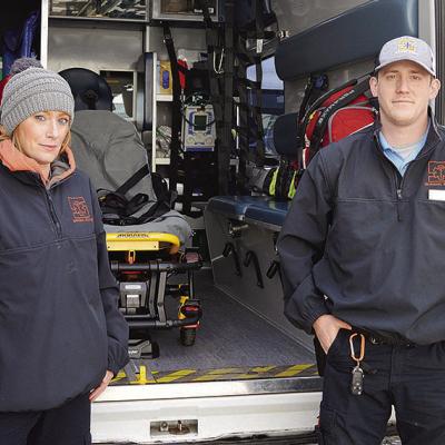 EMTs Marsha Shelton, left, and Payton Warnke stand outside a Sinor EMS ambulance making sure it is ready to roll. CDN | Hope King