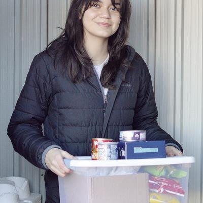 Carys Garcia carries a stack of donated food to the community food box she set up behind the Garcia Law offices Wednesday morning. CDN | Micah Ashcraft Carys Garcia carries a stack of donated food to the community food box she set up behind the Garcia Law offices Wednesday morning. CDN | Micah Ashcraft