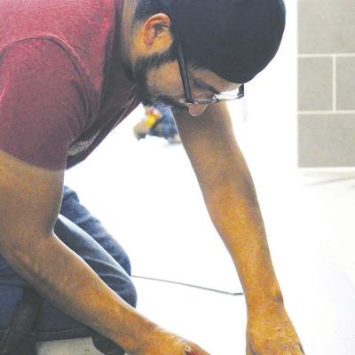 Joel Cruz, carefully measures flooring material before installation in a hallway of Southwest Elementary School. CDN | Sta photo Measuring floor