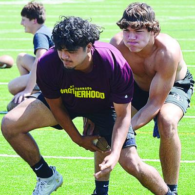 Clinton’s Aaron Ramirez, left, hikes the ball to sophomore quarterback Easten Powell during practice in the Tornado Bowl. CDN | Sam Goodwyn