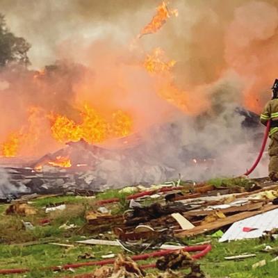 Firefighters battle a blaze early Tuesday morning following a home explosion 1/3 mile north of State Highway 73 on 2200 RD west of Clinton. Below a firefighter looks through the aftermath of the explosion. Two die in home explosion