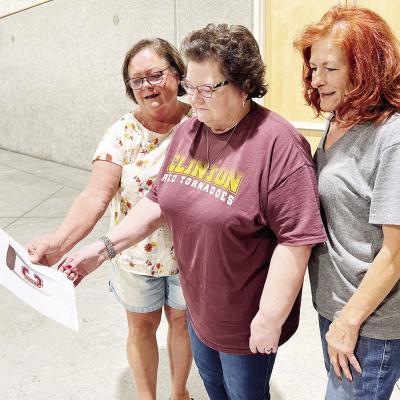 Looking at the first draft of a cup set to be sold at the Clinton High School All-School Reunion “Let the Good Times Roll,” from left, are Diana Kinney McClendon, Susan Farmer and Sandy Cornell. CDN | Emily Stephens Plans in works for All-School Reunion