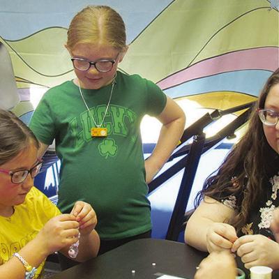 From left, Ela Thomas, Joslynn Roll, and Kat Brunelle design bracelets at a “K-Pop Demon Hunters” watch party at the Clinton Public Library. CDN | Christian Jacobsen