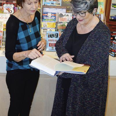 Oklahoma Route 66 Museum Director Pat Smith, left, and volunteer Pam Mosely examine one of the many books in the gift shop. CDN | Michael Maresh