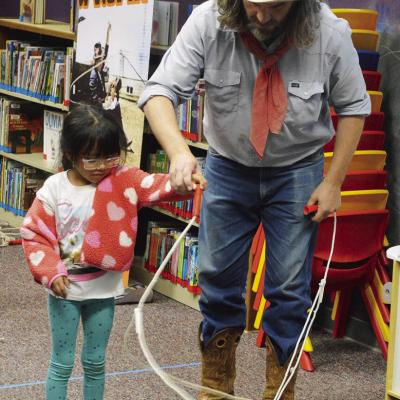 Annalise Gutierrez, left, gets help starting her lasso twirl by Buckaroo Bart Wednesday at the Clinton Public Library. CDN | Christian Jacobsen