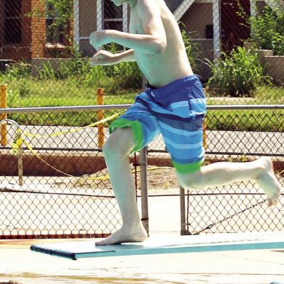 Summer Playground student Justin Schenewolf runs off the diving board to make a big splash into the pool. CDN | Emily Stephens Preparing for a big splash!