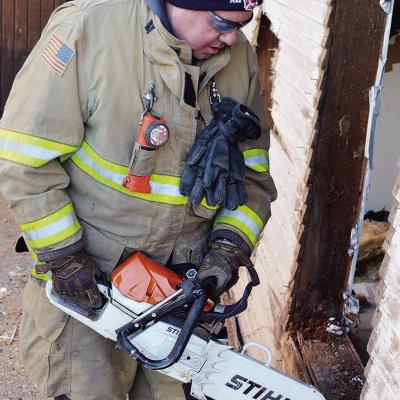 Clinton Firefighter John Denney cuts into the side of a house at 1011 Avant Ave. as part of a Saturday morning training exercise. CDN | Michael Maresh
