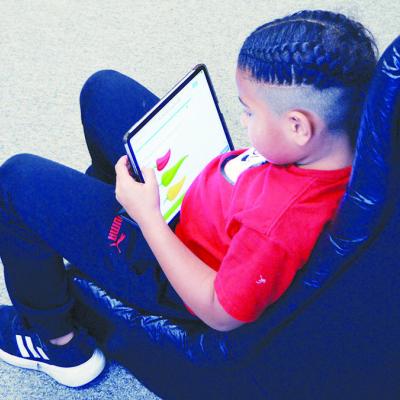 First-grader Otha Douglas uses a tablet to study.