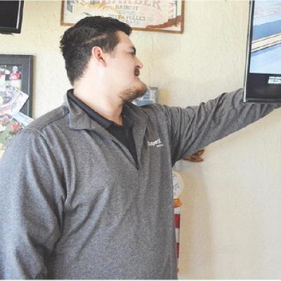 Wesley Flores helps set up the wired internet for the different TV displays at Adam’s Edge Barbershop. CDN | Micah Ashcraft
