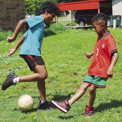 Kyi Williams, left, and Josiah Reece go head-to-head for the ball while playing front yard soccer. CDN | Micah Ashcraft