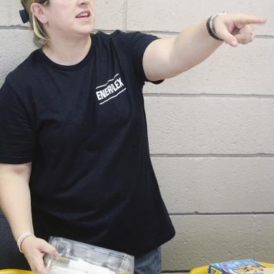 Katie Daugherty, a Whirlwinds booster parent, helps pack meals for a football scrimmage directing where to put the finished bags. CDN | Elisha Rangel Packing meals