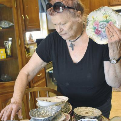 Naomi Oligney prepares her plate collections for the upcoming townwide garage sale this weekend. Residents are reminded to submit their garage sale listings to the Clinton Daily News. CDN | Elisha Rangel Pricing treasures