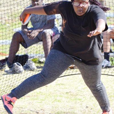 Clinton sophomore Lola Hester spins and sets up to throw the discus at practice, while teammate Montiel Crane looks on behind net. CDN | Collin Wieder Clinton track gets ready for final stretch