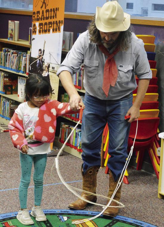 Annalise Gutierrez, left, gets help starting her lasso twirl by Buckaroo Bart Wednesday at the Clinton Public Library. CDN | Christian Jacobsen